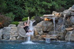 Woman Going Down Slide into Swimming Pool